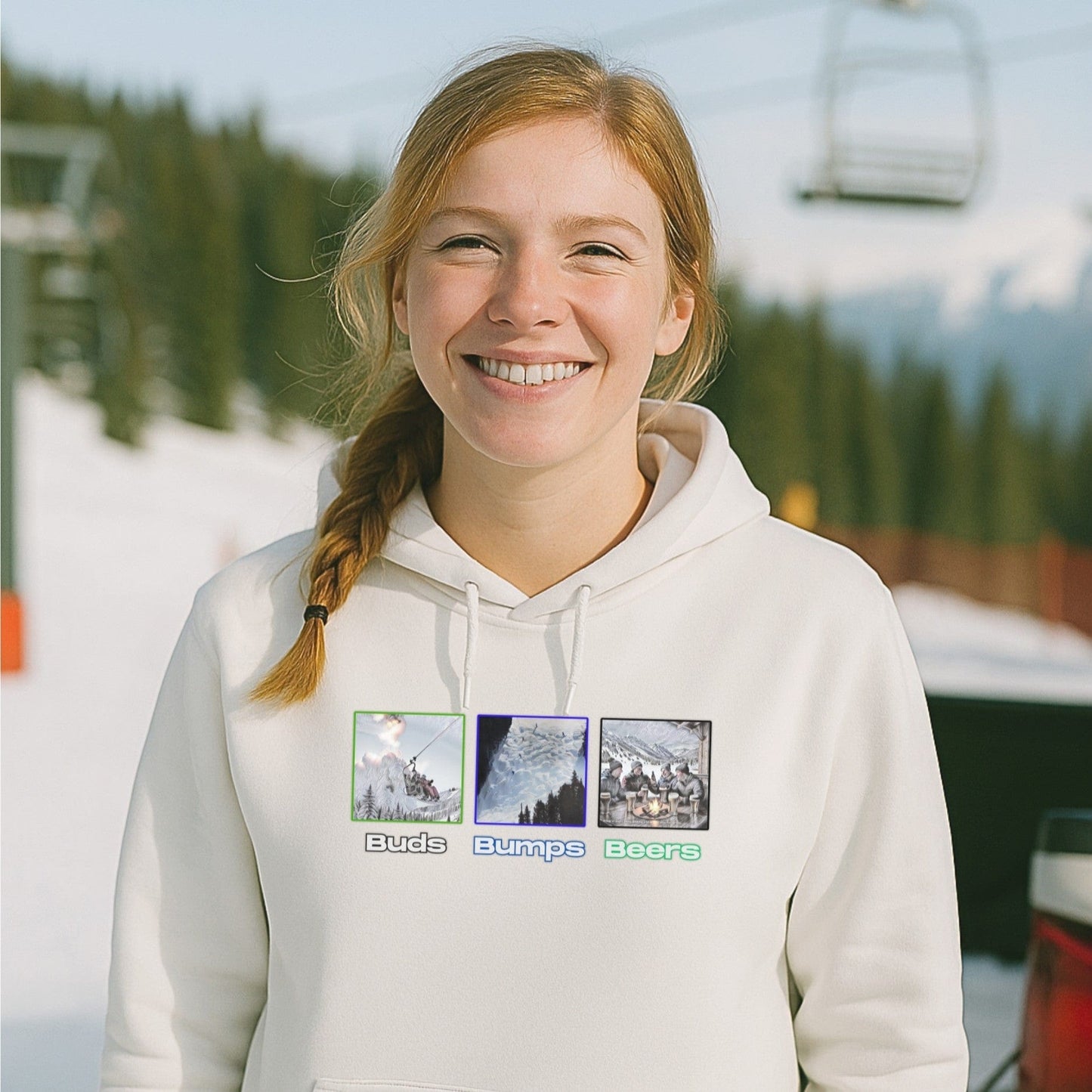White hoodie with the buds bumps beers design, worn by a smiling skier near the base of a lift on a sunny mountain morning.