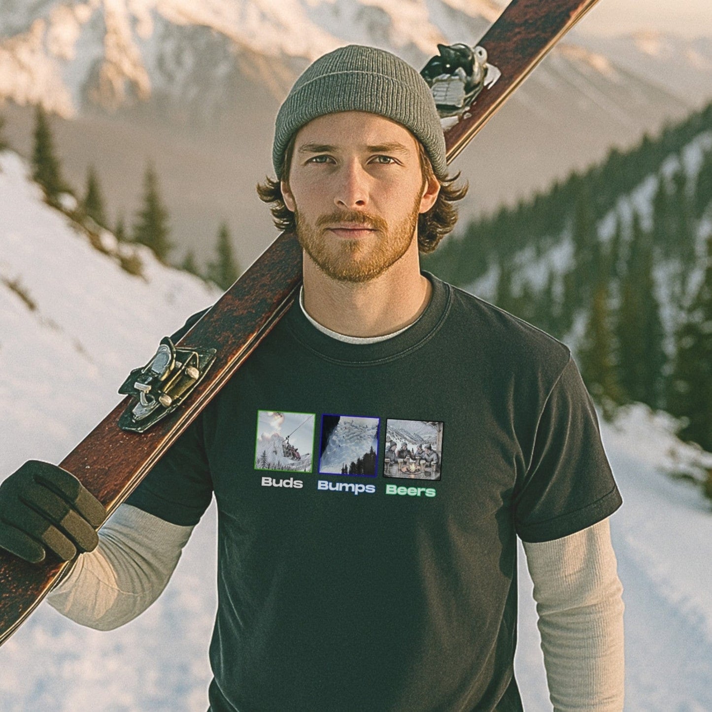 Man in black “Buds, Bumps, Beers” T-shirt holding skis on shoulder, standing on a snowy mountain trail during golden hour.