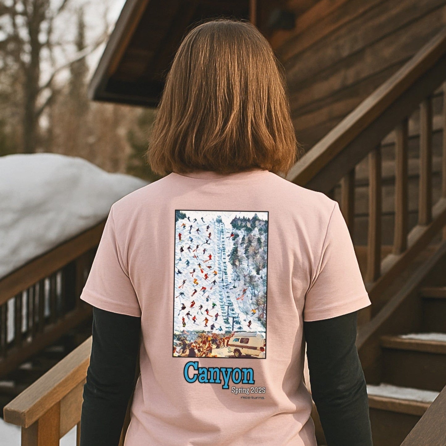 skier wearing light pink canyon spring 2025 T-shirt with ski lift graphic while walking up snow-covered lodge steps