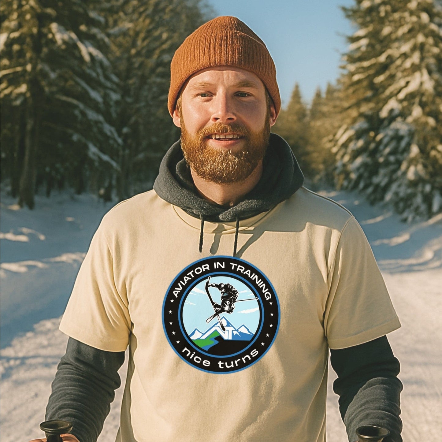 Aviator in Training tee from nice turns in natural color, worn over a hoodie on a snowy ski trail during golden hour.