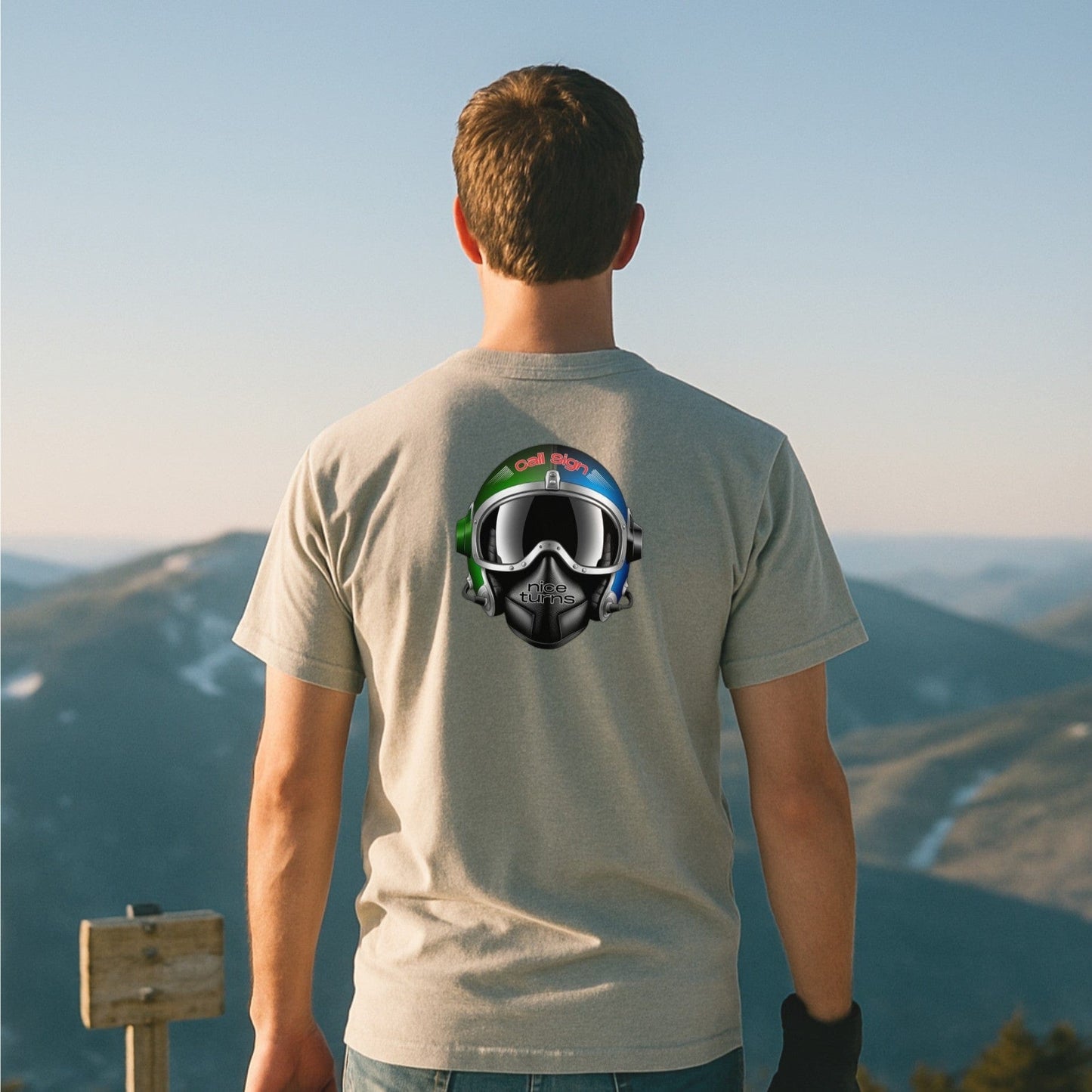 Light grey t-shirt with nice turns Call Sign helmet graphic on the back, worn overlooking a mountain range at golden hour.