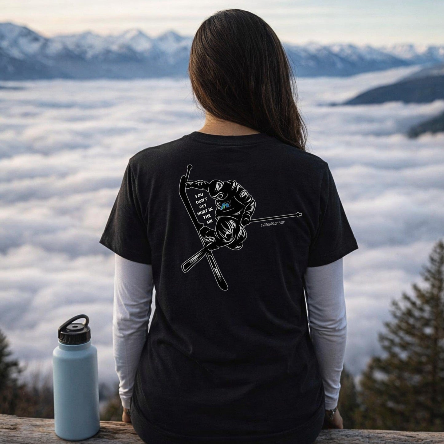 Female skier wearing black t-shirt with back jump graphic overlooking mountain view