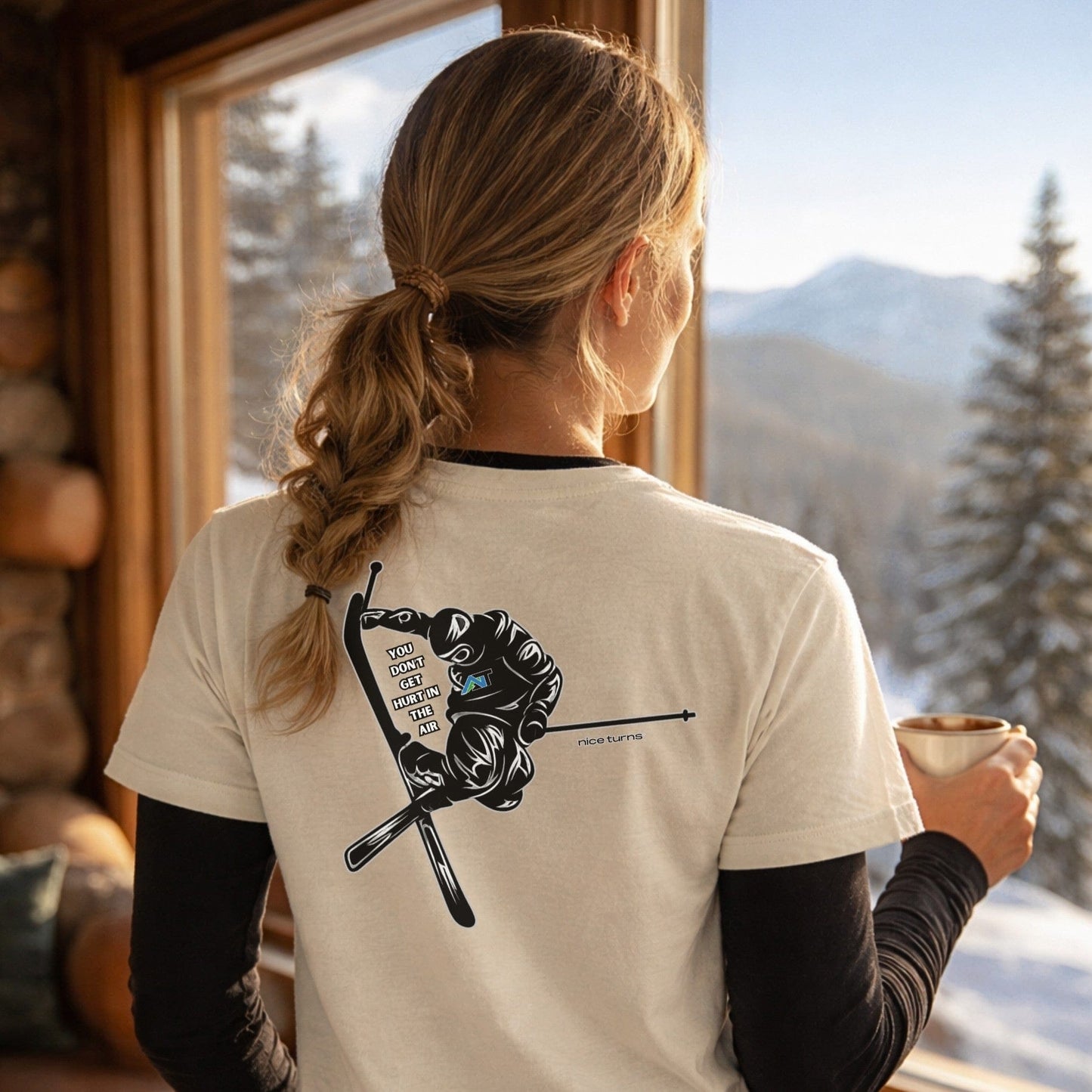 Female skier wearing natural t-shirt with back jump graphic looking out mountain window