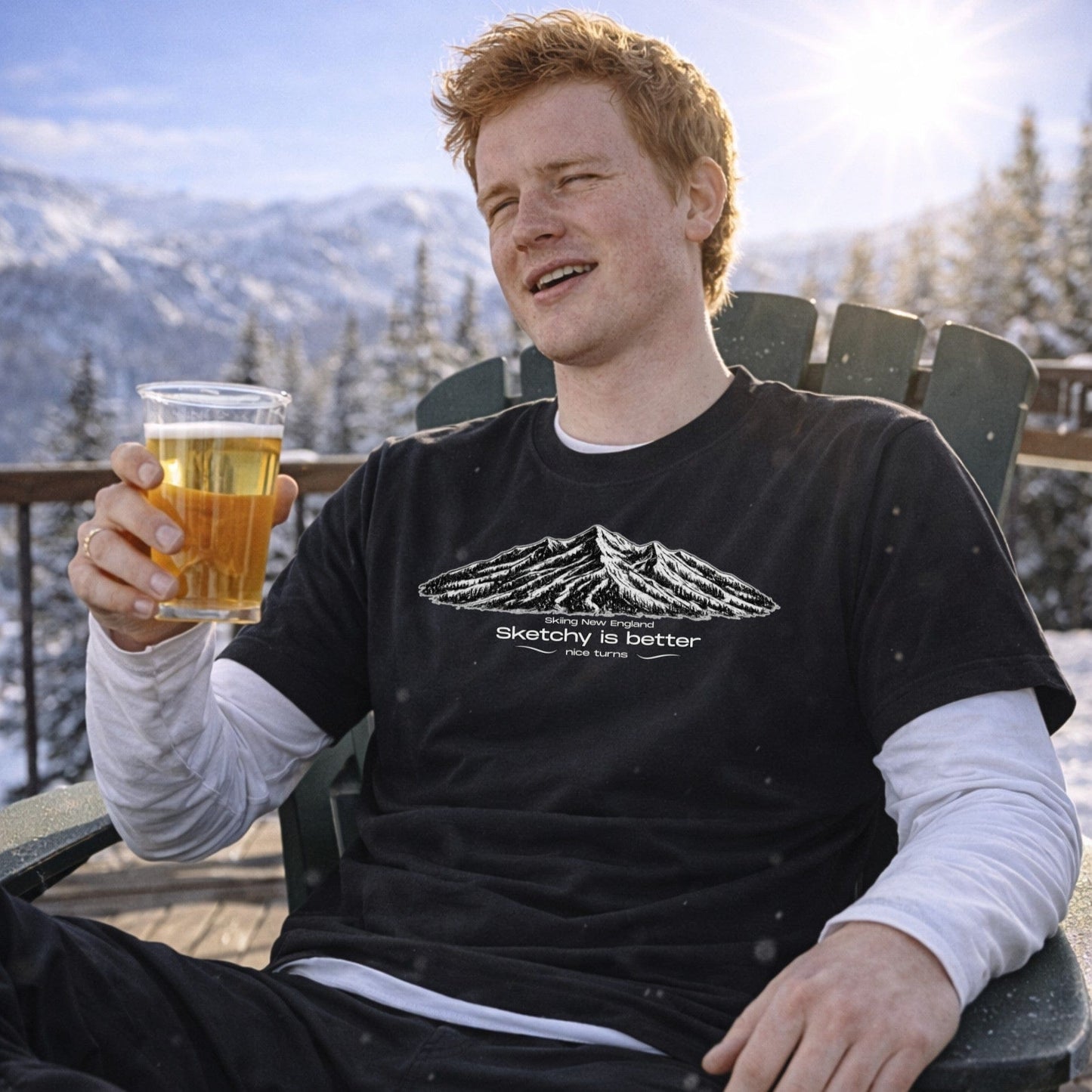 Male skier wearing navy mountain sketch t-shirt holding beer outdoors