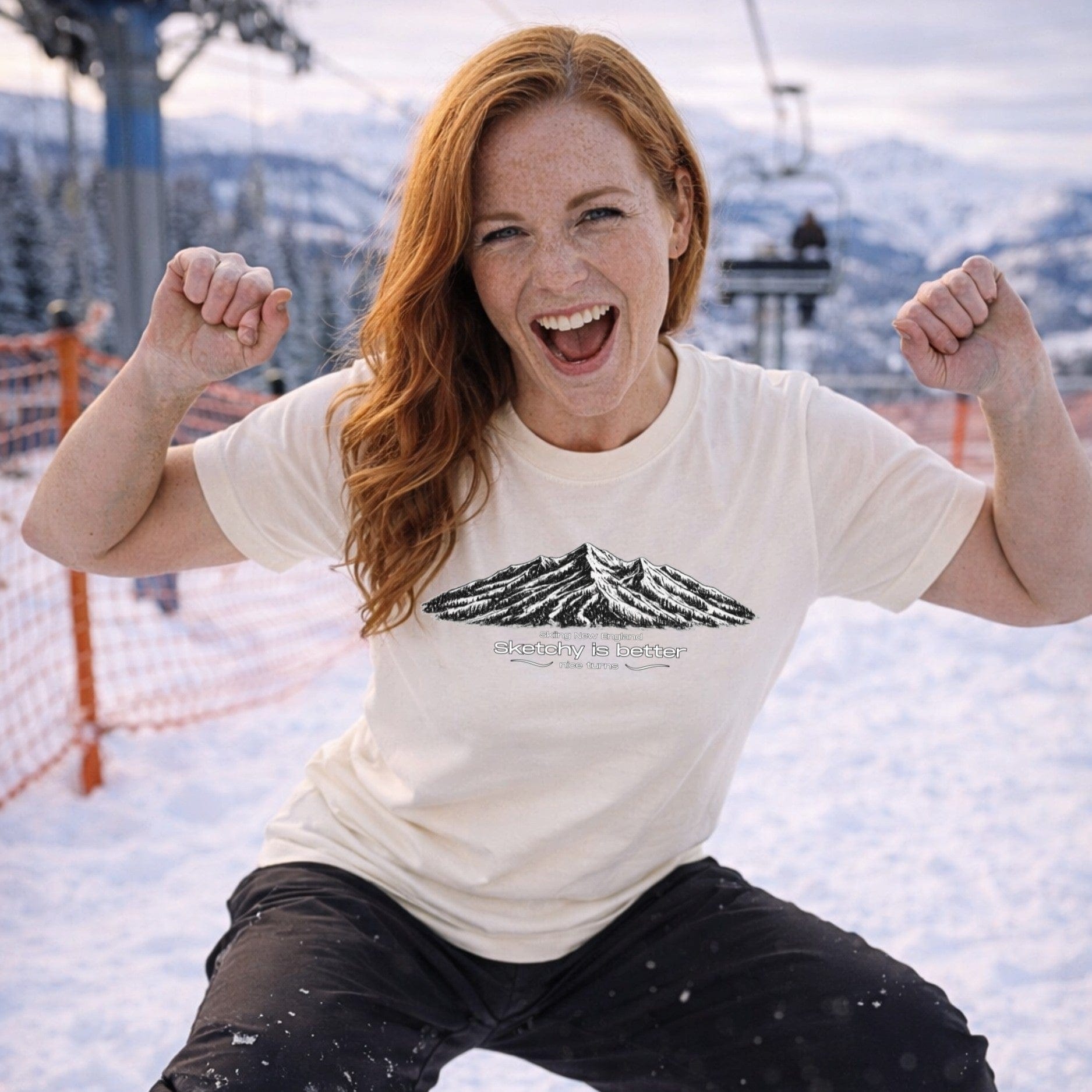 Female skier wearing cream mountain sketch t-shirt celebrating on slope
