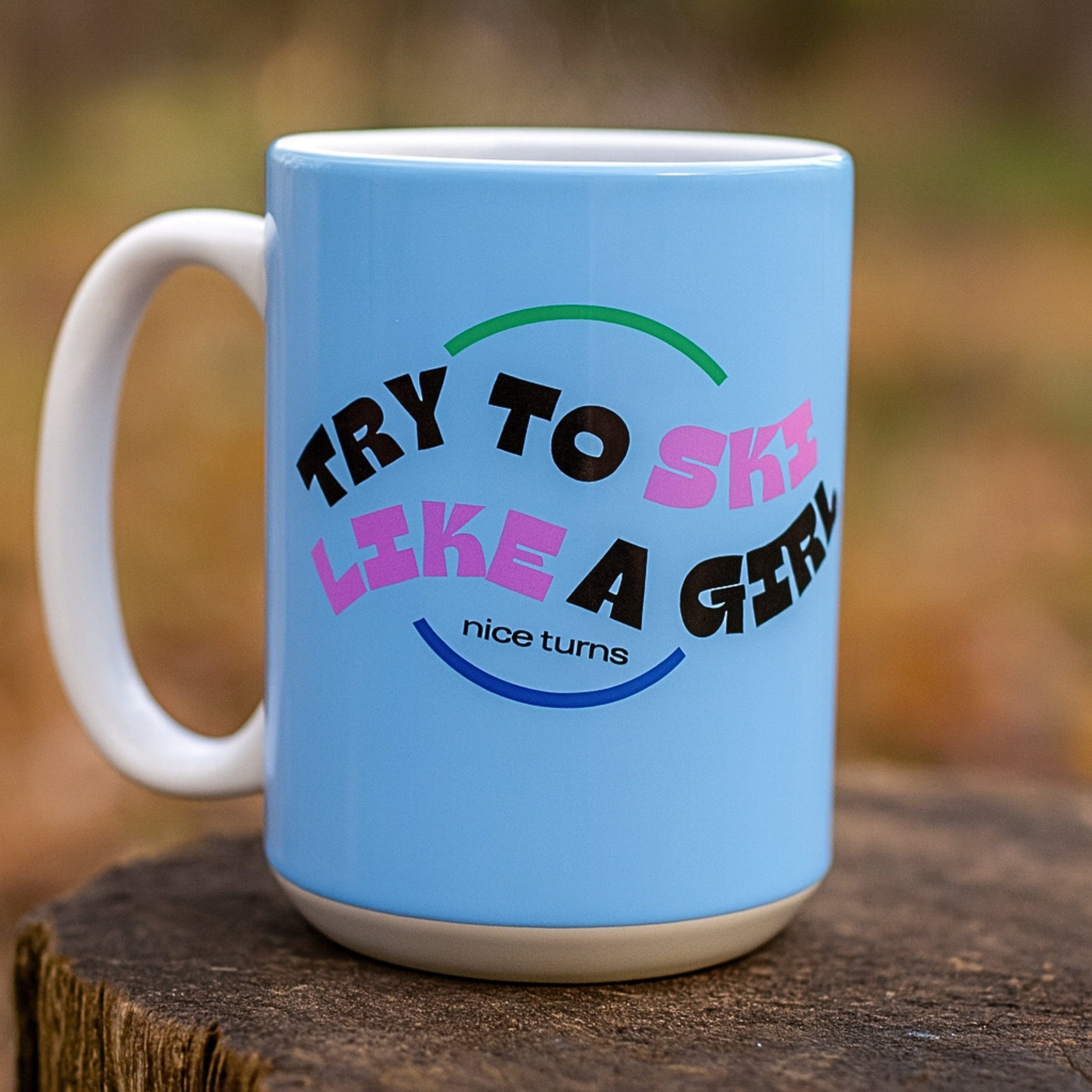 ChatGPT said:

Freida Ridge 15 oz coffee mug, Cool Blue, outdoors on tree stump with visible steam; centered “Try to Ski Like a Girl” wraparound graphic.