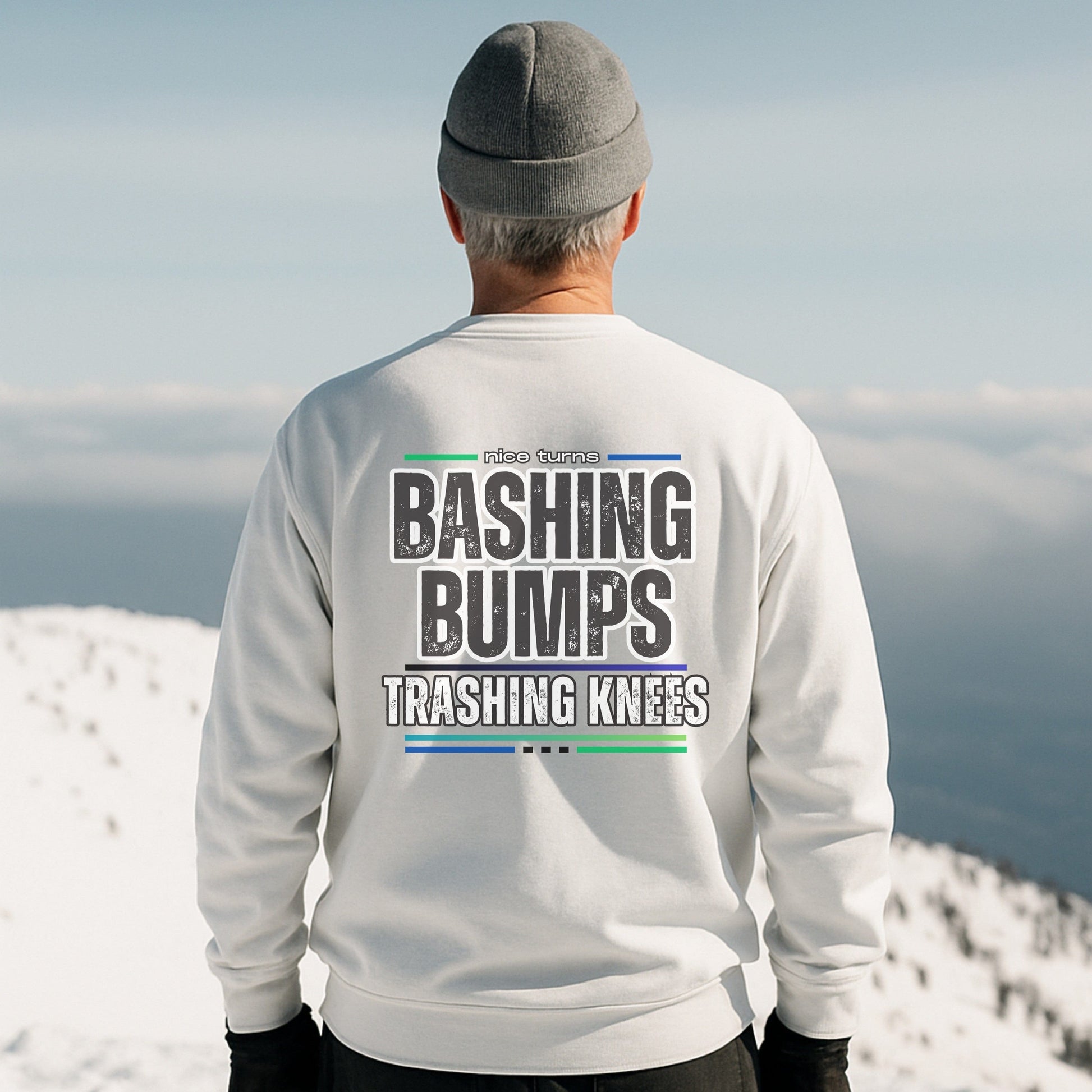 Bashing Bumps Sweatshirt, white, back lifestyle view on snowy ridgeline; bold “Trashing Knees” ski graphic across shoulders; relaxed fleece fit.