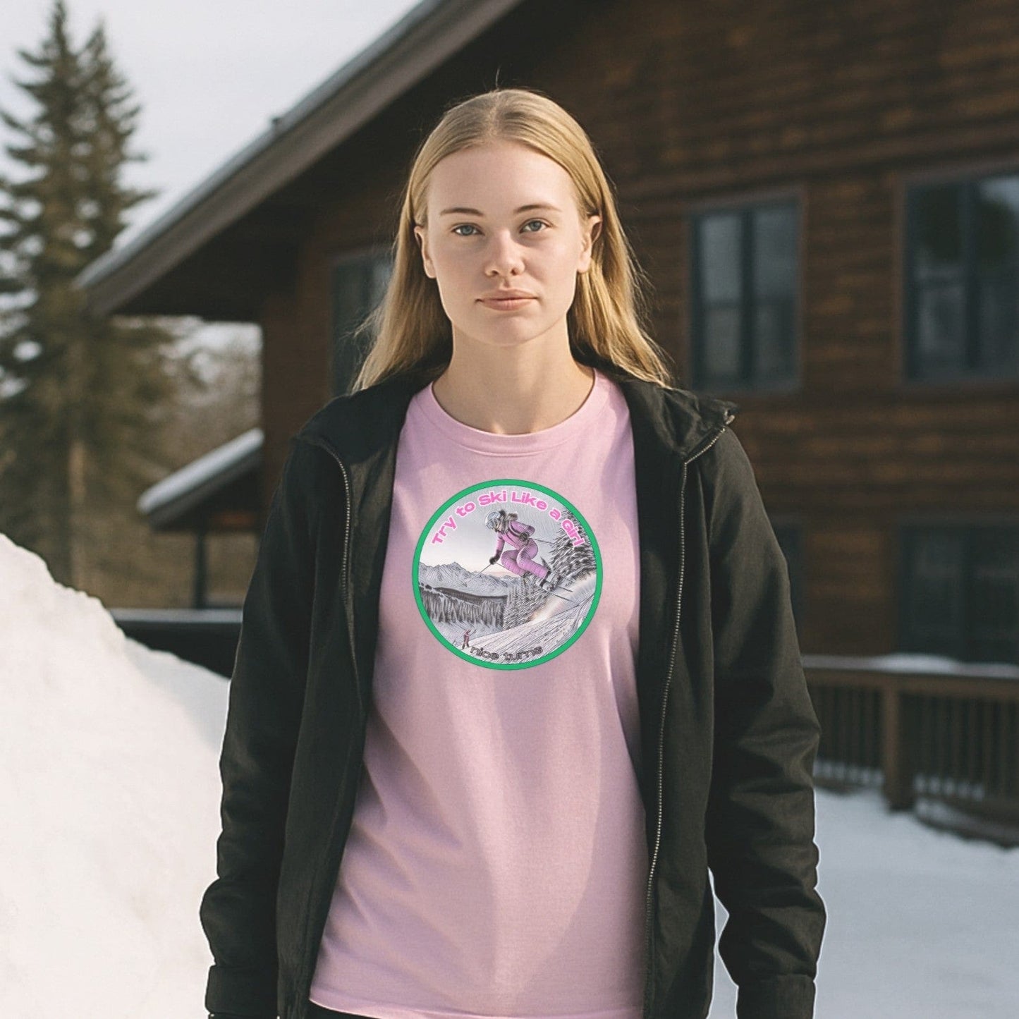 Light pink t-shirt with "Try to Ski Like a Girl" skier design, worn outside a snowy mountain cabin with pine trees in the background.