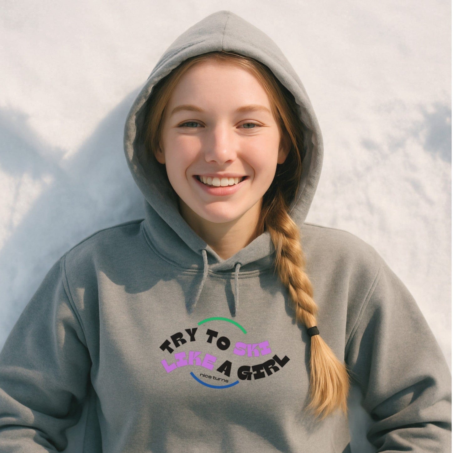Gray hoodie with “Try to Ski Like a Girl” design, worn by a young skier smiling in the snow after a day on the mountain.