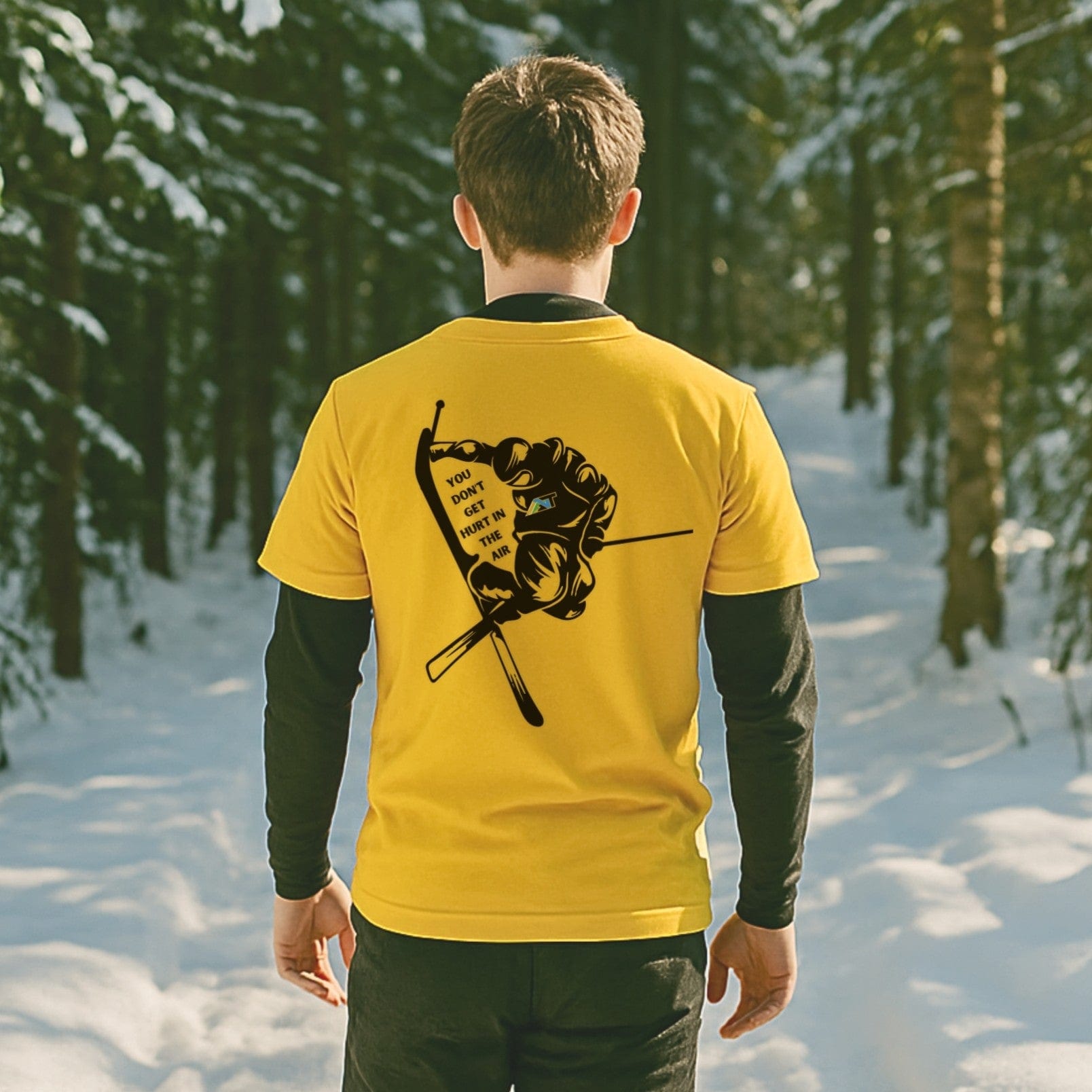 skier walking snowy glade trail in gold T-shirt with pole grab ski graphic and mountain quote
